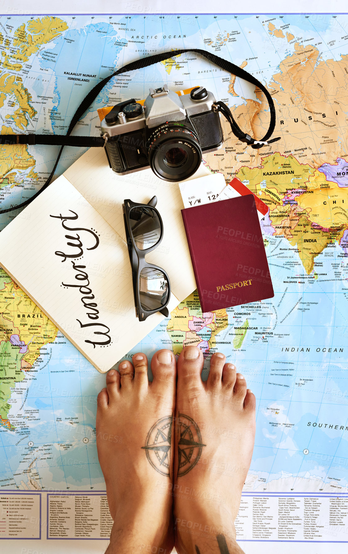 Buy stock photo High angle shot of a young tourist's feet standing on a map with a notebook, camera and passport arranged on it