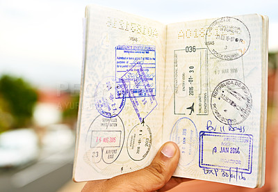 Buy stock photo Shot of an unidentifiable young man holding open a passport full of visa stamps
