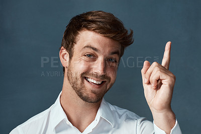 Buy stock photo Studio portrait of a handsome young man pointing to copyspace against a dark background