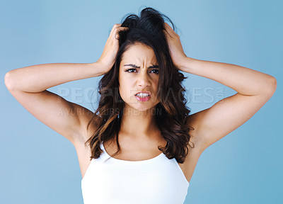 Buy stock photo Studio shot of an attractive young woman looking frustrated against a blue background