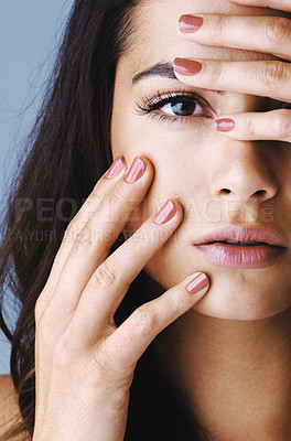 Buy stock photo Studio shot of an attractive young woman touching her face to show off her beautiful nails against a gray background