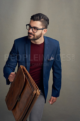 Buy stock photo Studio shot of a handsome young man carrying a bag against a grey background