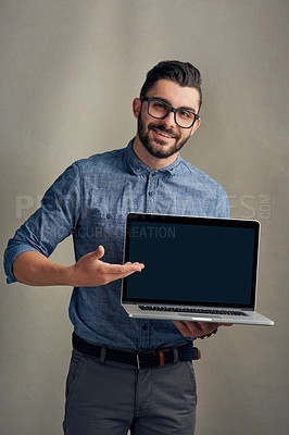 Buy stock photo Studio portrait of a young man holding a laptop against a grey background
