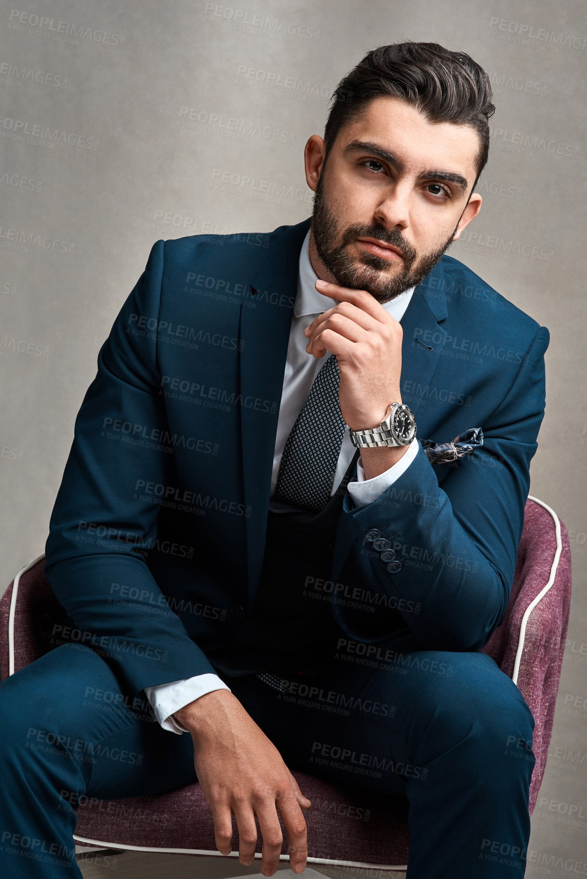Buy stock photo Studio portrait of a stylishly dressed young businessman sitting on a chair against a grey background