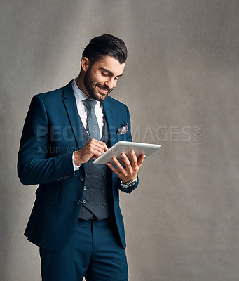 Buy stock photo Studio shot of a stylishly dressed young businessman using a digital tablet against a grey background