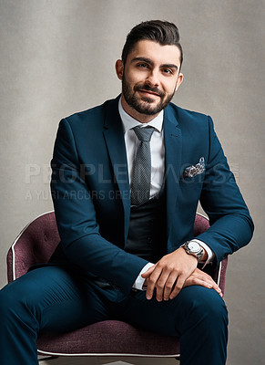 Buy stock photo Studio portrait of a stylishly dressed young businessman sitting on a chair against a grey background