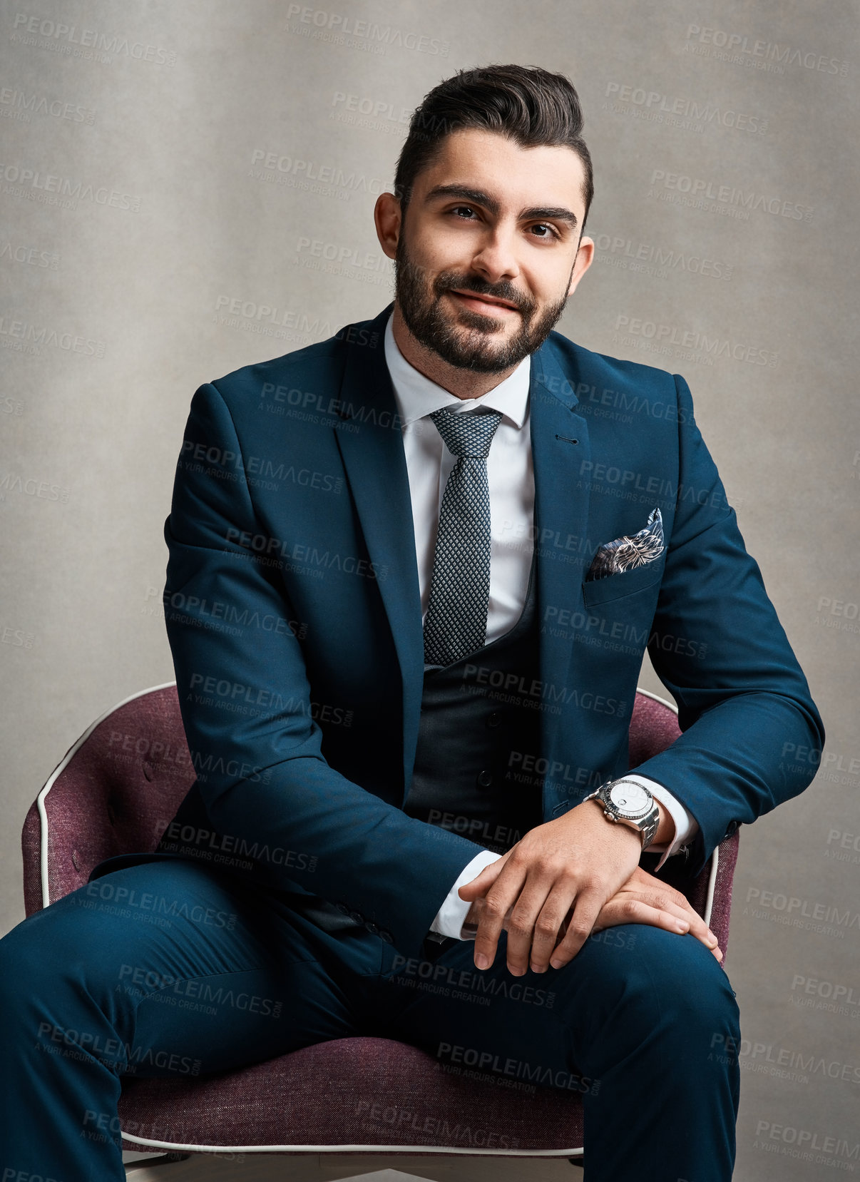 Buy stock photo Studio portrait of a stylishly dressed young businessman sitting on a chair against a grey background