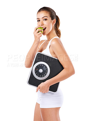 Buy stock photo Cropped shot of a young woman eating an apple while holding a scale