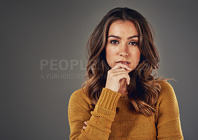 Buy stock photo A studio portrait of a young Caucasian woman thinking and looking doubtful isolated on a grey background. Skeptic and nervous, posing with a hand on her face. A woman looking depressed and helpless.