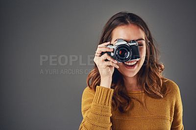 Buy stock photo Portrait of an attractive young woman taking photographs against a grey background