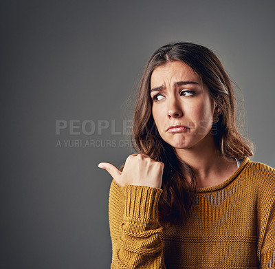 Buy stock photo Shot of an unhappy-looking young woman standing against a grey background