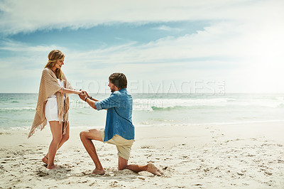 Buy stock photo Full length shot of a young man proposing to his girlfriend on the beach