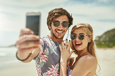 Buy stock photo Shot of an affectionate young couple taking selfies after their engagement on the beach