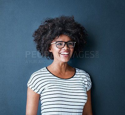 Buy stock photo Studio shot of an attractive and happy young woman wearing glasses against a blue background