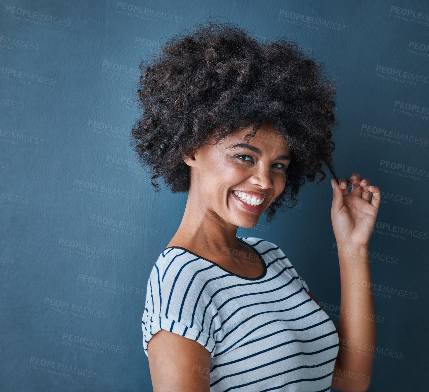 Buy stock photo Girl, portrait and pull curly hair in studio with confidence for growth, results and smile by blue background. African person, woman and model with texture, happy and change with cosmetics for afro