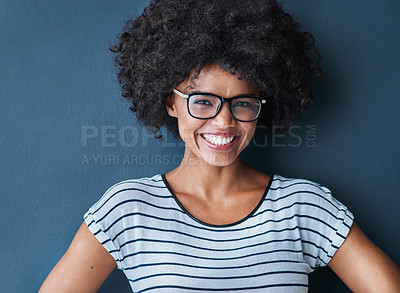 Buy stock photo Studio portrait of an attractive and confident young woman wearing glasses against a blue background