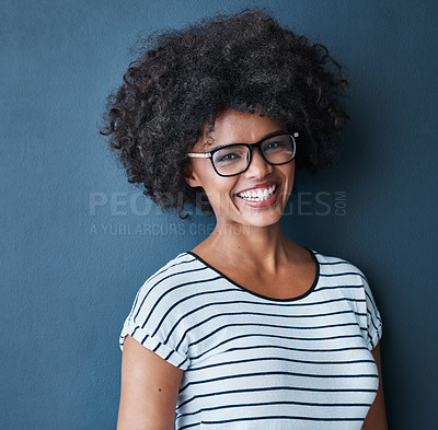 Buy stock photo Studio portrait of an attractive and happy young woman wearing glasses against a blue background