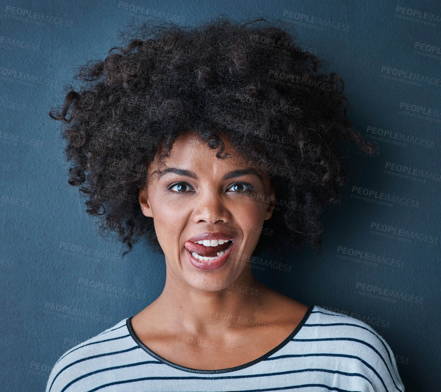 Buy stock photo Portrait, tongue and black woman with facial expression in studio for fun, relax and playful attitude on blue background. Lady, comic and goofy emoji with a funny face, crazy and personality isolated