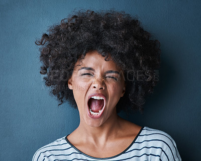 Buy stock photo Studio portrait of an attractive young woman screaming against a blue background