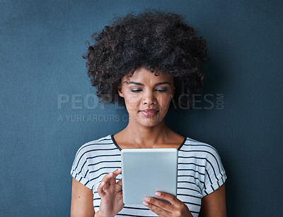 Buy stock photo Studio shot of an attractive young woman using a digital tablet against a blue background