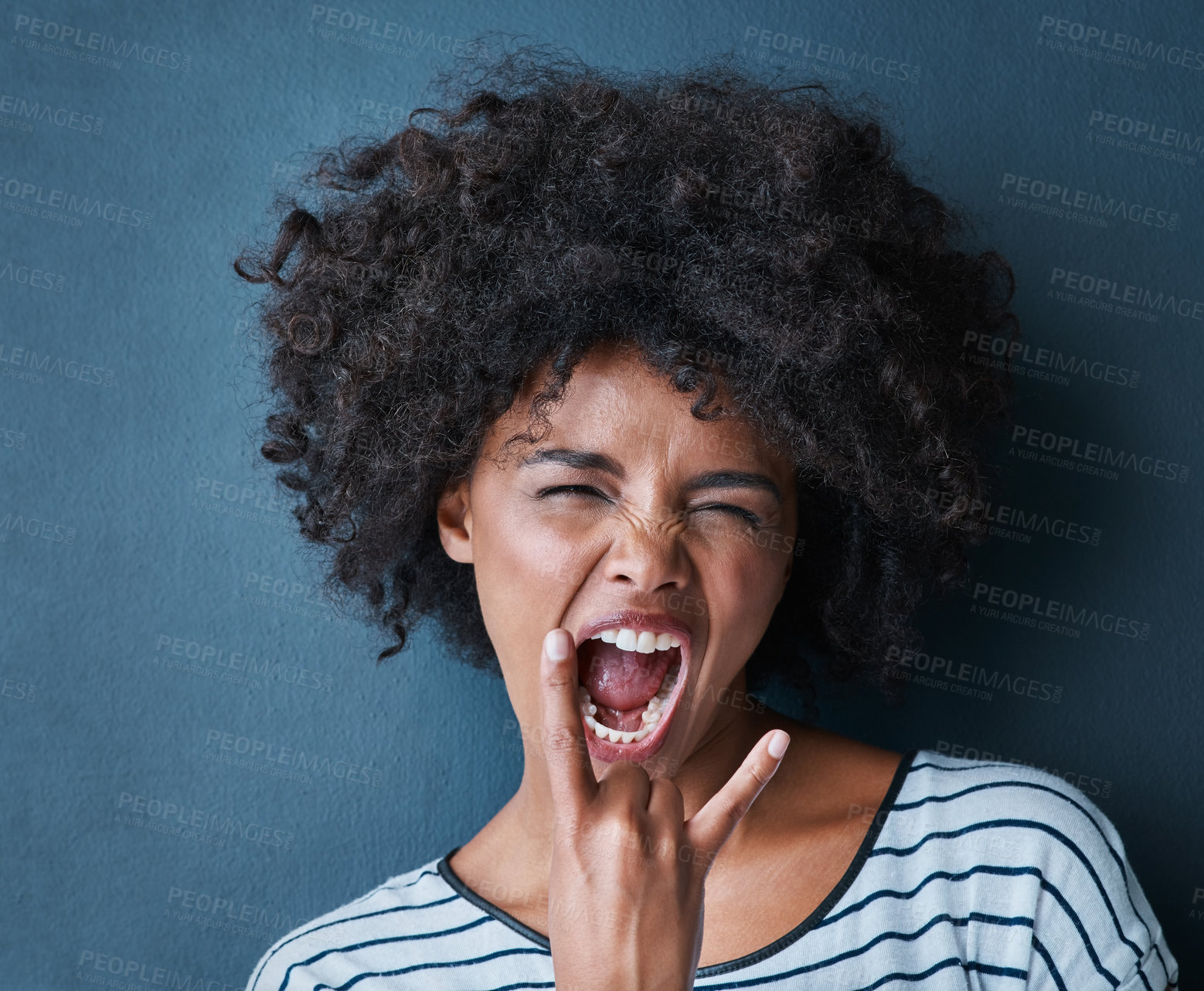 Buy stock photo Black woman, emoji and rocker with facial expression in studio for fun, relax and playful attitude on blue background. Lady, comic and goofy portrait with a funny face, crazy and personality isolated