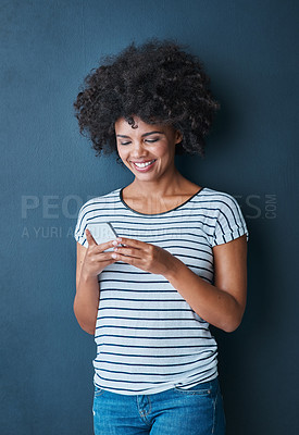 Buy stock photo Studio shot of an attractive young woman using a mobile phone against a blue background