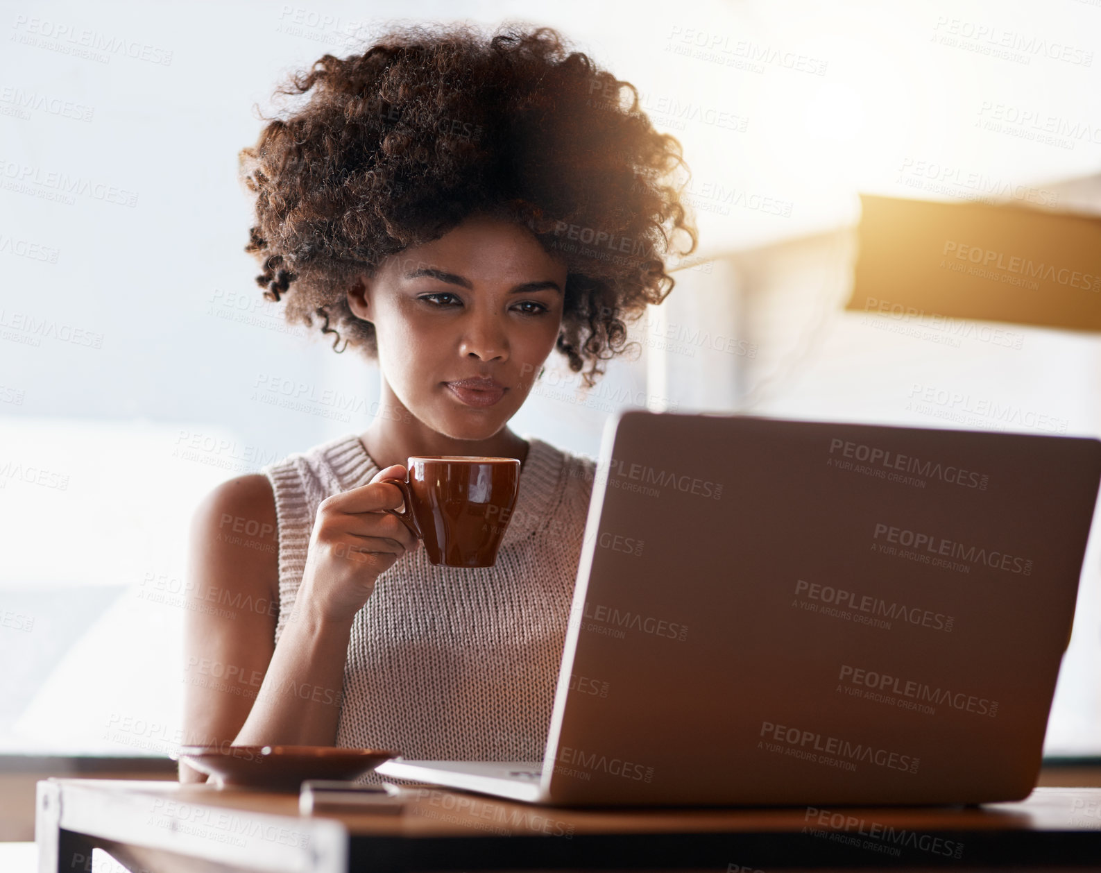 Buy stock photo Shot of a young business owner using a laptop while sitting in her cafe
