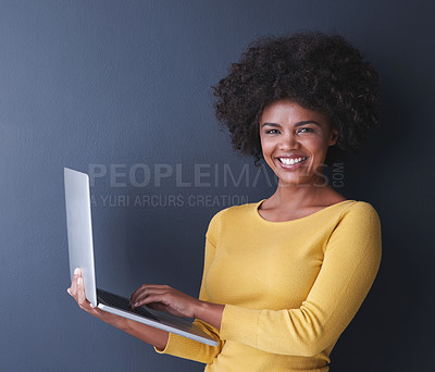 Buy stock photo Studio shot of a young woman using her laptop against a grey background