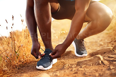 Buy stock photo Cropped shot of an unidentifiable man tying his shoelaces before a run outside