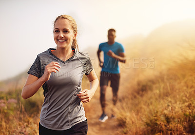 Buy stock photo Cropped shot of two sporty young people out for a run together