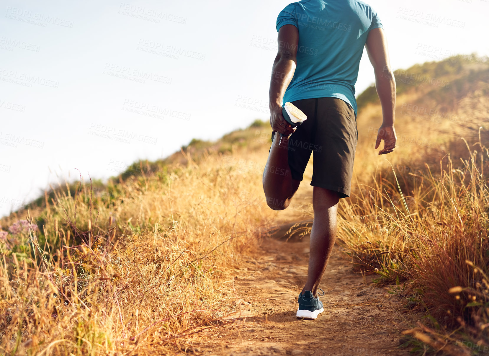 Buy stock photo Rear view shot of an unidentifiable young man stretching before a run outside