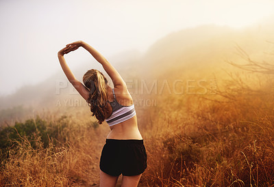 Buy stock photo Rear view shot of a sporty young woman stretching before a run outside