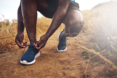 Buy stock photo Cropped shot of an unidentifiable man tying his shoelaces before a run outside