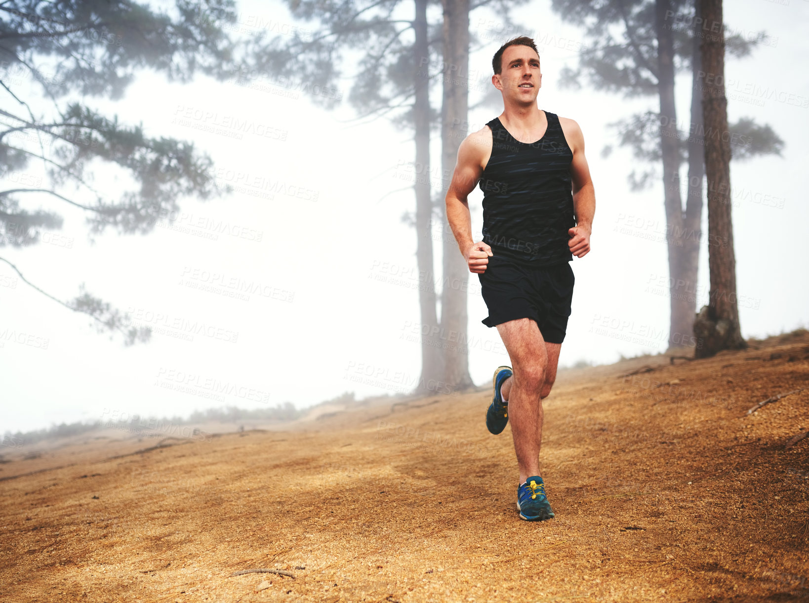 Buy stock photo Shot of a sporty young man out for a run in the forest