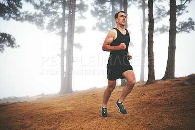 Buy stock photo Shot of a sporty young man out for a run in the forest