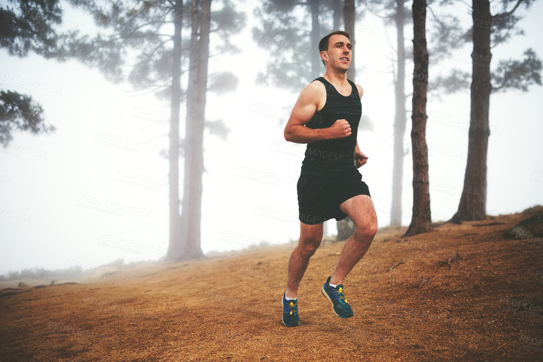 Buy stock photo Shot of a sporty young man out for a run in the forest