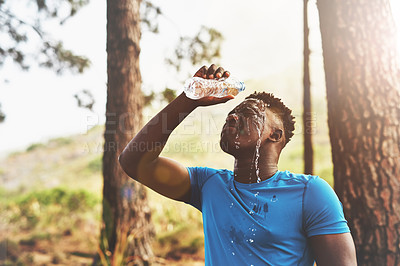 Buy stock photo Cropped shot of a sporty young man pouring water over his face while out for a run in the forest