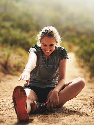 Buy stock photo Shot of a sporty young woman stretching before a run outside