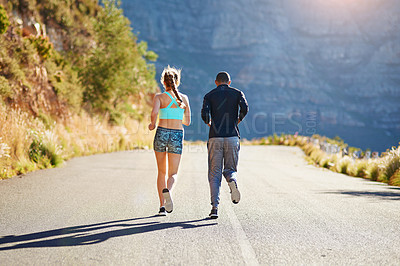 Buy stock photo Rear view shot of a sporty young couple out for a run together