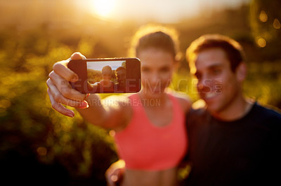 Buy stock photo Cropped shot of a sporty young couple taking a selfie while out for a run together