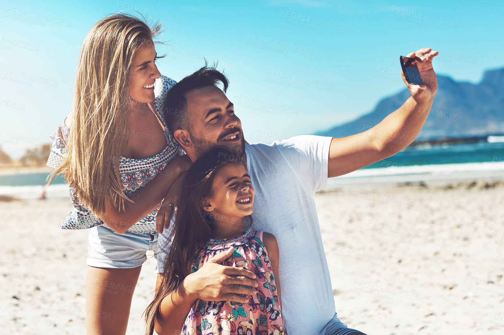 Buy stock photo Cropped shot of a happy young family enjoying their day at the beach