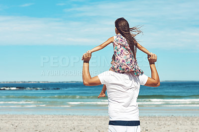 Buy stock photo Rearview shot of a young father and his daughter enjoying a day at the beach