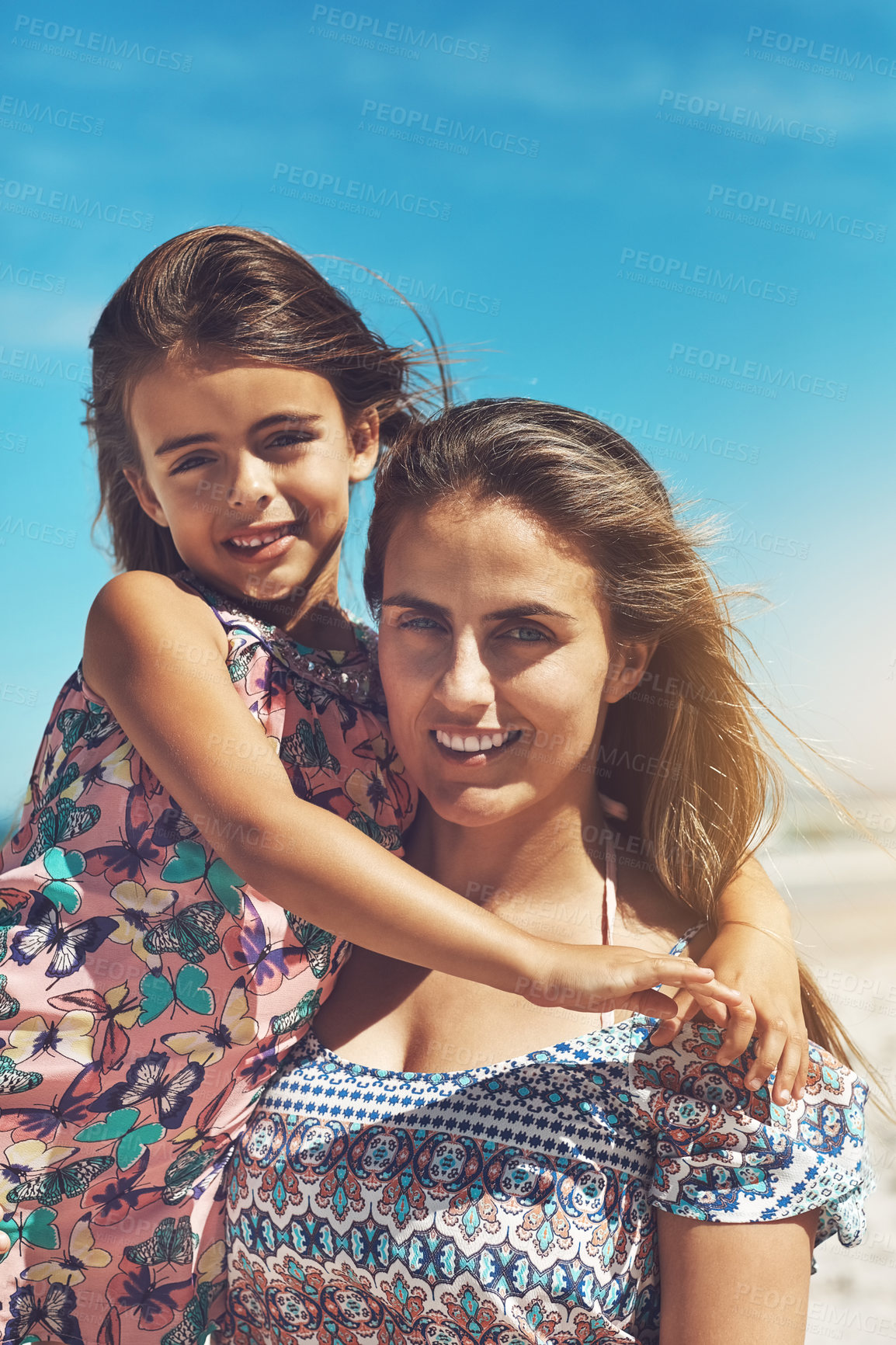 Buy stock photo Cropped portrait of a young mother and her daughter enjoying a day at the beach