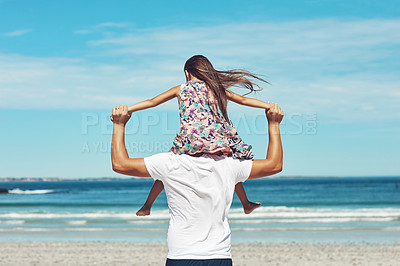 Buy stock photo Rearview shot of a young father and his daughter enjoying a day at the beach
