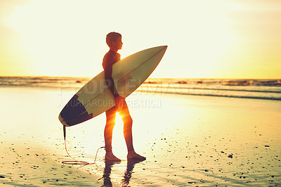 Buy stock photo Shot of a young surfer holding his surfboard while looking towards the ocean
