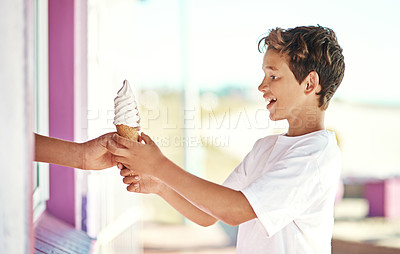 Buy stock photo Shot of a happy young boy getting an ice-cream cone from a shop by the beach