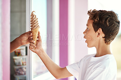 Buy stock photo Shot of a happy young boy getting an ice-cream cone from a shop by the beach