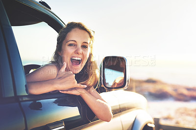 Buy stock photo Cropped portrait of an attractive young woman making a surfing gesture while on a roadtrip