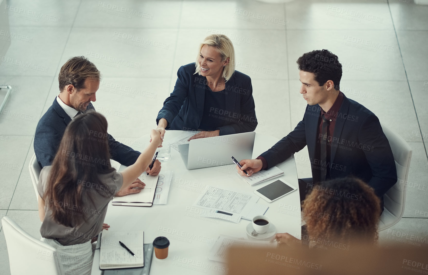 Buy stock photo Shot of two businesswomen shaking hands during a meeting in a modern office