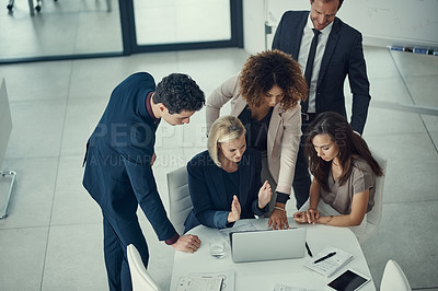 Buy stock photo Shot of a group of colleagues using laptop together during a meeting in a modern office